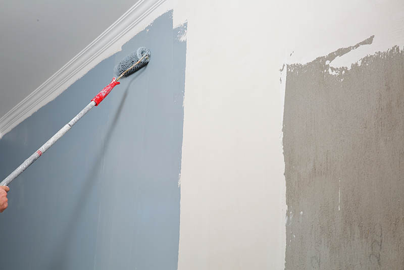 Paint roller painting white wall with blue paint | McAuliffe Painting